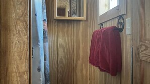 Ein Holzinnenraum mit einem Spiegel, einem roten Handtuch und einem Fenster.