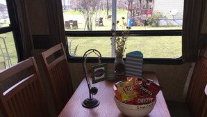 A table with a bowl of snacks, a welcome sign, and a view of the outdoors. - Hookem.Hideout I (Quitman)