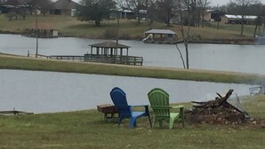 A lakeside view with a gazebo, chairs, and a pile of wood. - Hookem.Hideout I (Quitman)