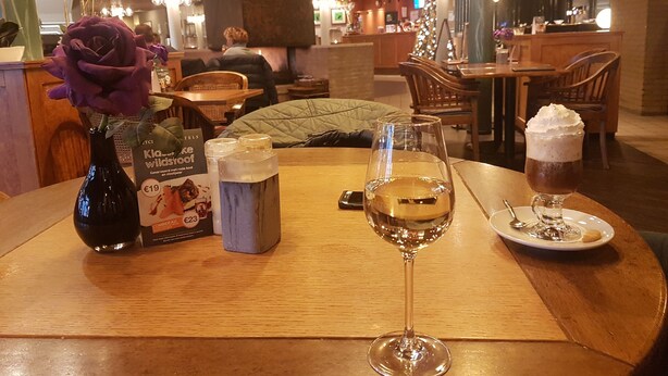 Ein Tisch mit einer Flasche, einem Glas, einer Speisekarte und einer Nachspeise.