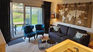 Ein modernes Wohnzimmer mit einer Couch, zwei Sesseln, einem Couchtisch und einer Weltkarte an der Wand.