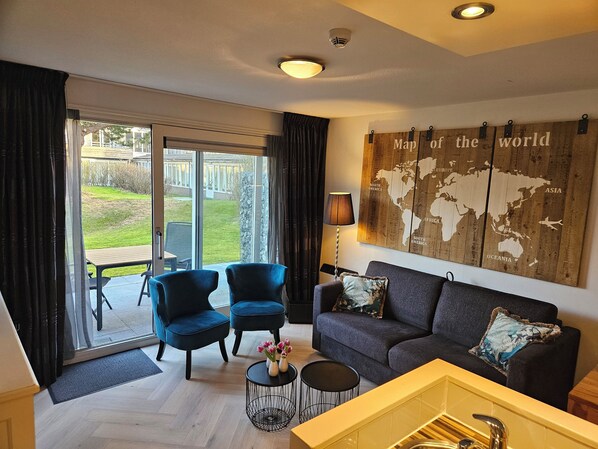 Een moderne woonkamer met een bank, twee fauteuils, een salontafel en een wereldkaart aan de muur.