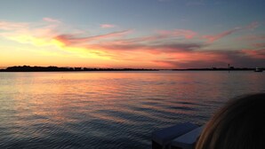 A sunset over a calm body of water with a distant shoreline. - ON EAGLE BEACH Costa Linda Beach Resort (oranjestad)
