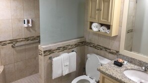 A bathroom with a toilet, sink, towel rack, and a shower area. - ON EAGLE BEACH Costa Linda Beach Resort (oranjestad)