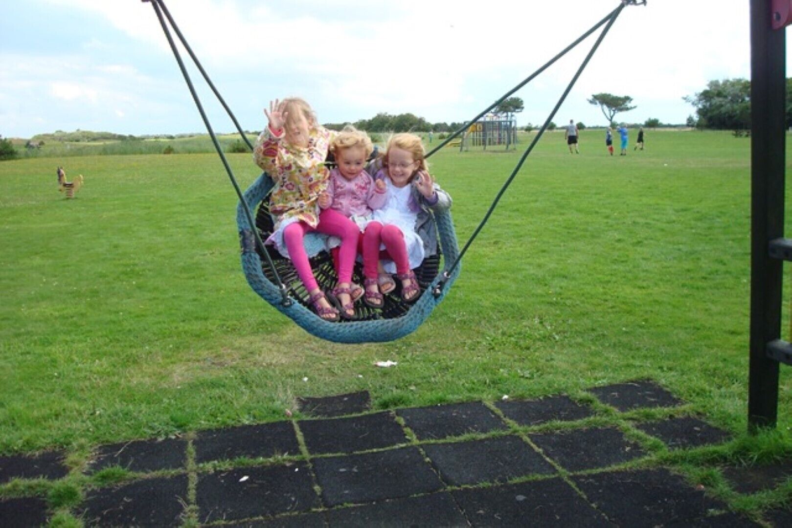 A swing set in a grassy field with a clear sky.