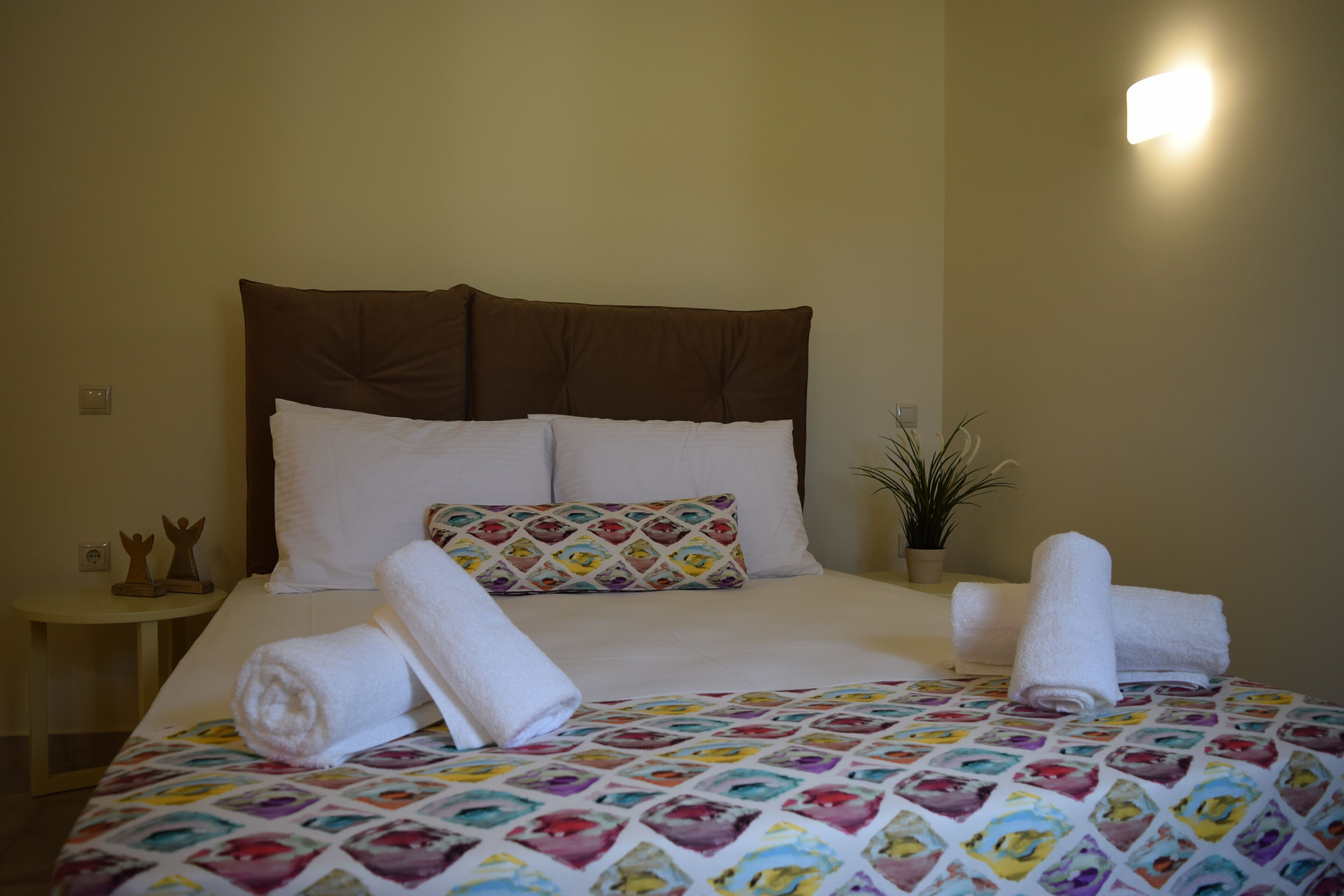 A neatly made bed with a colorful quilt, a brown headboard, and white pillows.