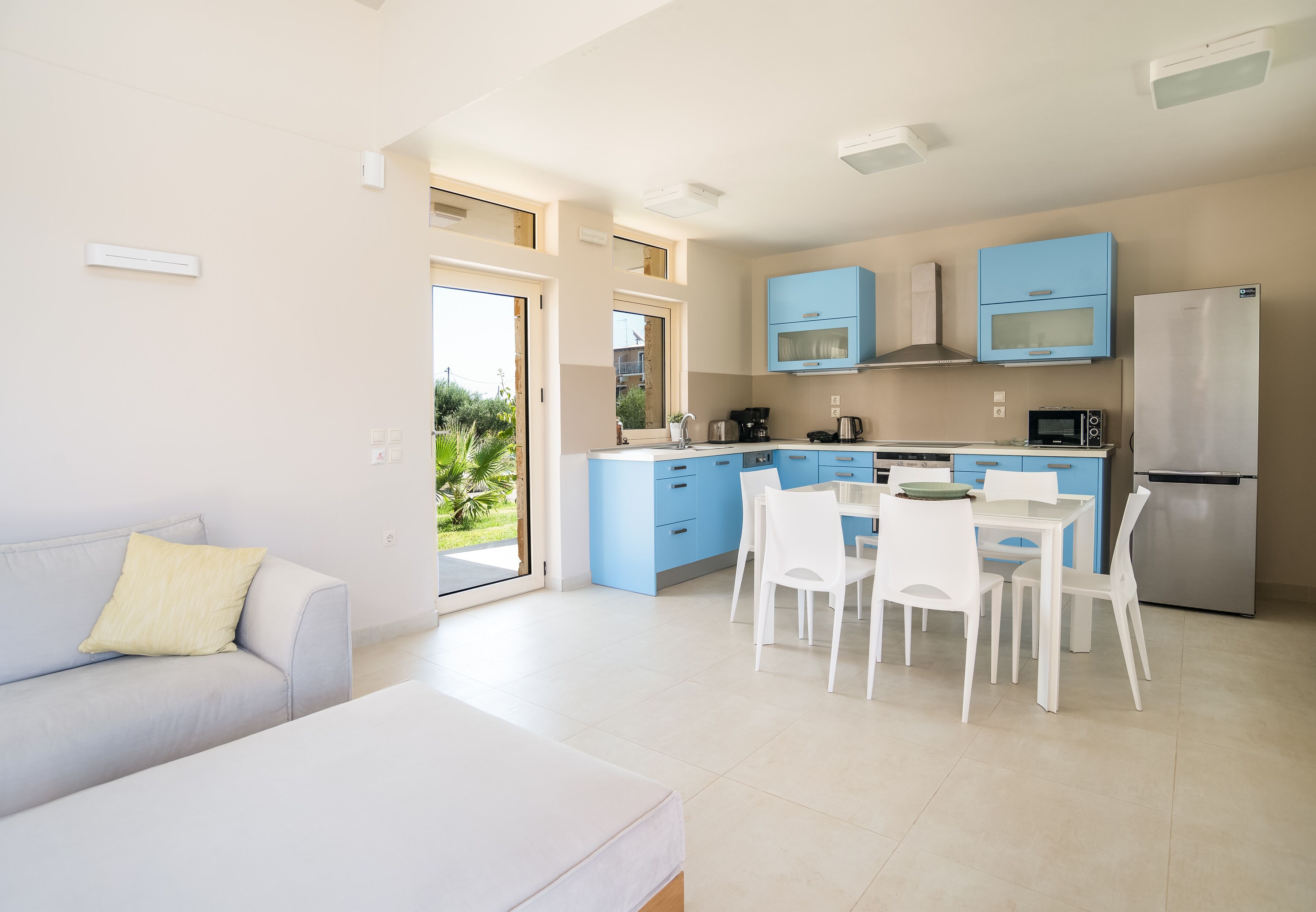Una cocina moderna con armarios azules, una mesa de comedor blanca y sillas.