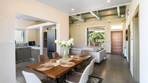 A dining area with a wooden table, woven placemats, and white chairs. - Three Stars Luxury Villas (Corfu)