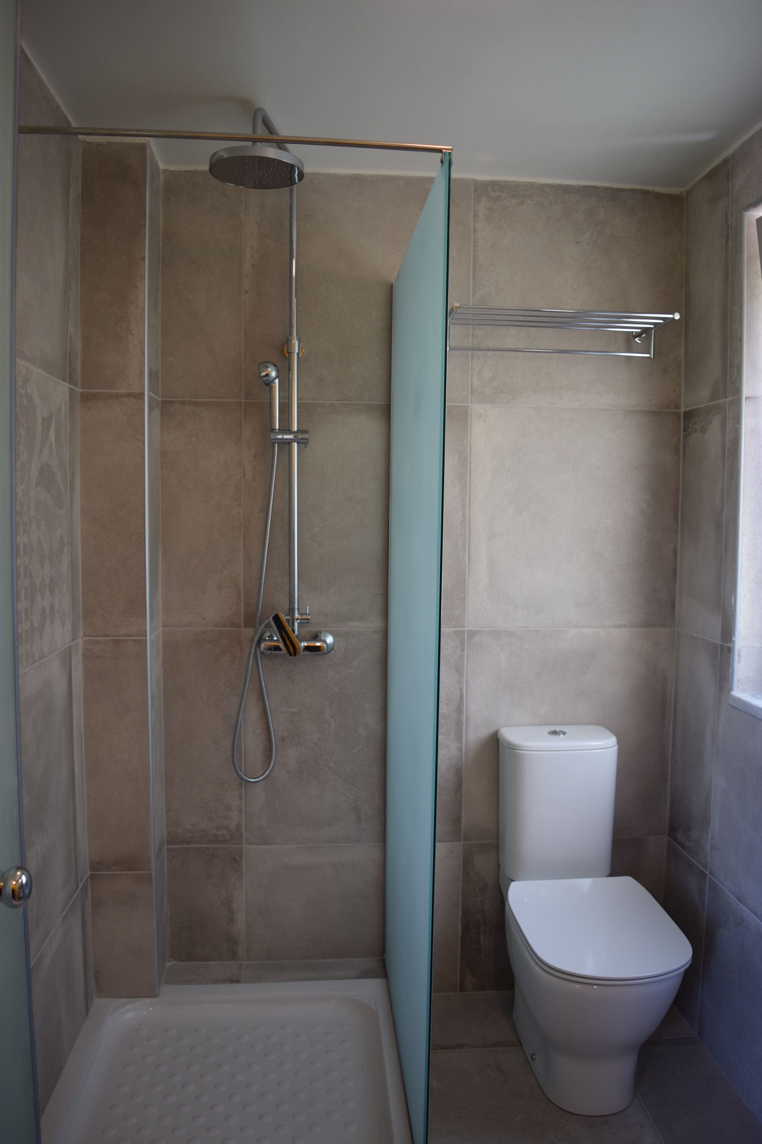 Ein Badezimmer mit Dusche, Toilette und einer Glasabtrennung.