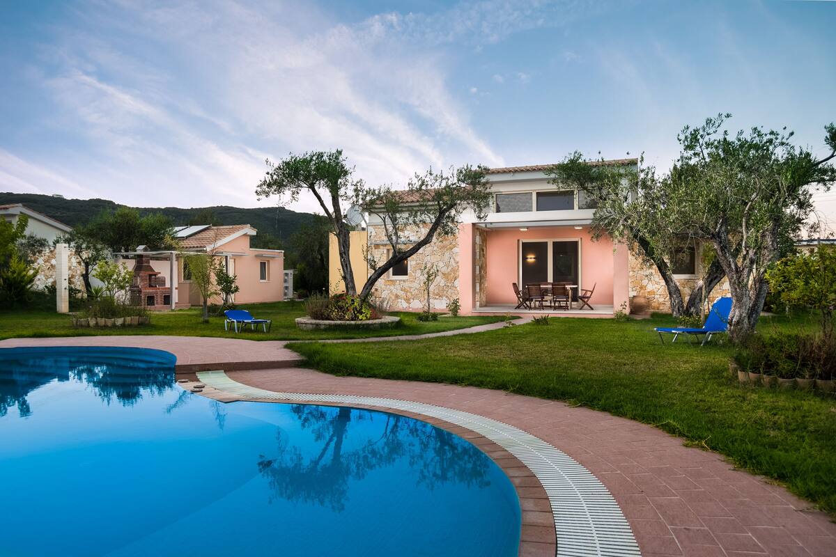 Una propiedad residencial con piscina, un patio amoblado y un edificio de piedra con tejado de baldosas.