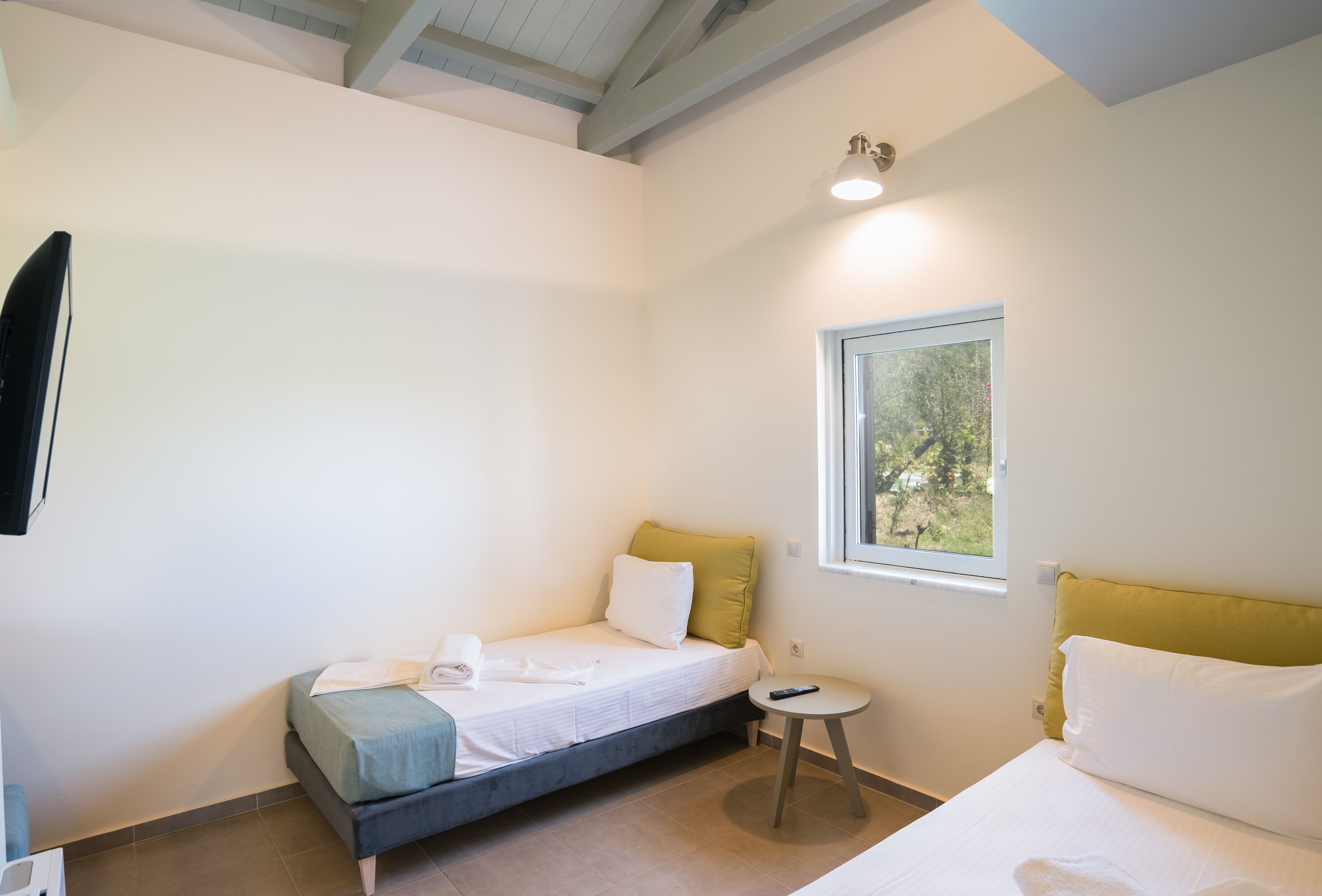Een kleine, goed verlichte kamer met een bed, een tafeltje en een raam.