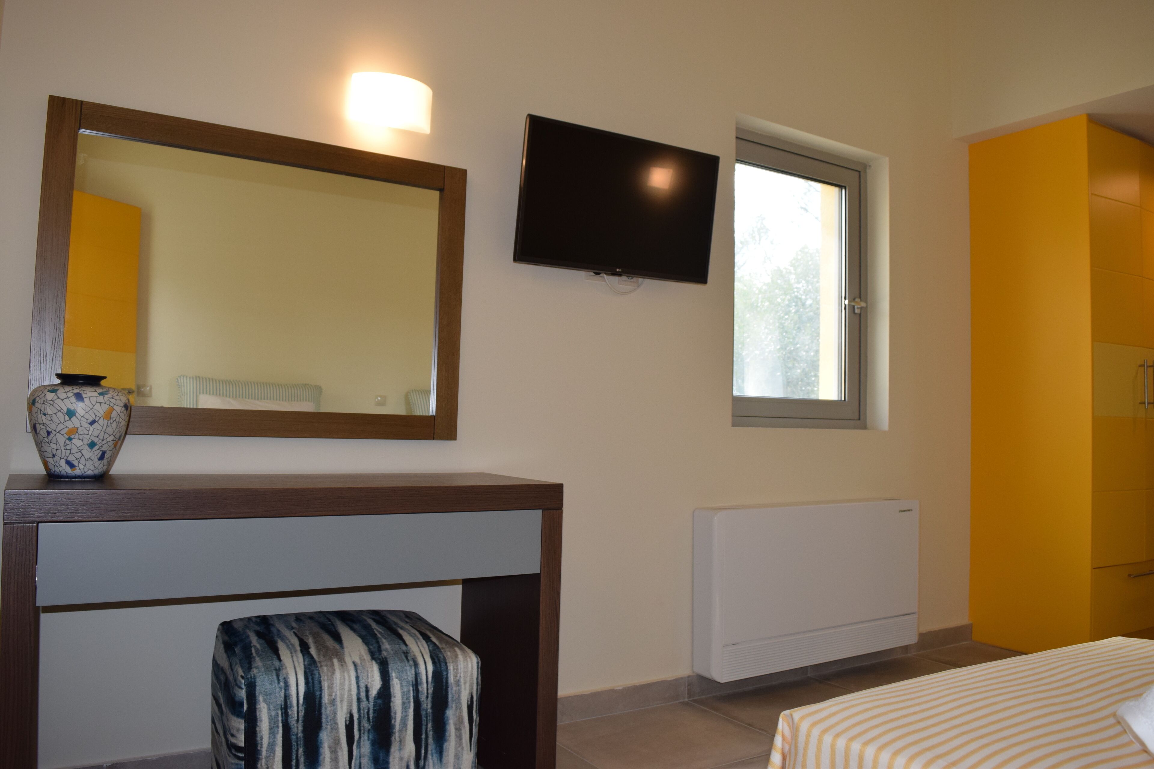 Ein Schlafzimmer mit einem Bett, einem an der Wand montierten Fernseher, einem Fenster und einer Heizung.