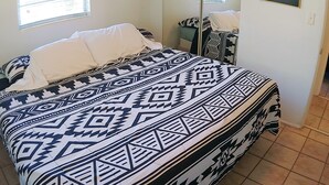 A bed with a patterned bedspread, a mirror, and artwork on the walls. - Mid Century Charm! KSC,Port Canaveral,Cocoa and Bio-Lume Kayak,Pet Friendly! (Titusville)