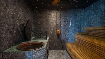 Relax in a sauna room with a wooden bench, ceiling fan, and stone wall.