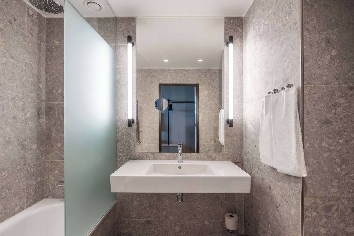 A modern bathroom with a rectangular sink, a mirror, and a towel rack.