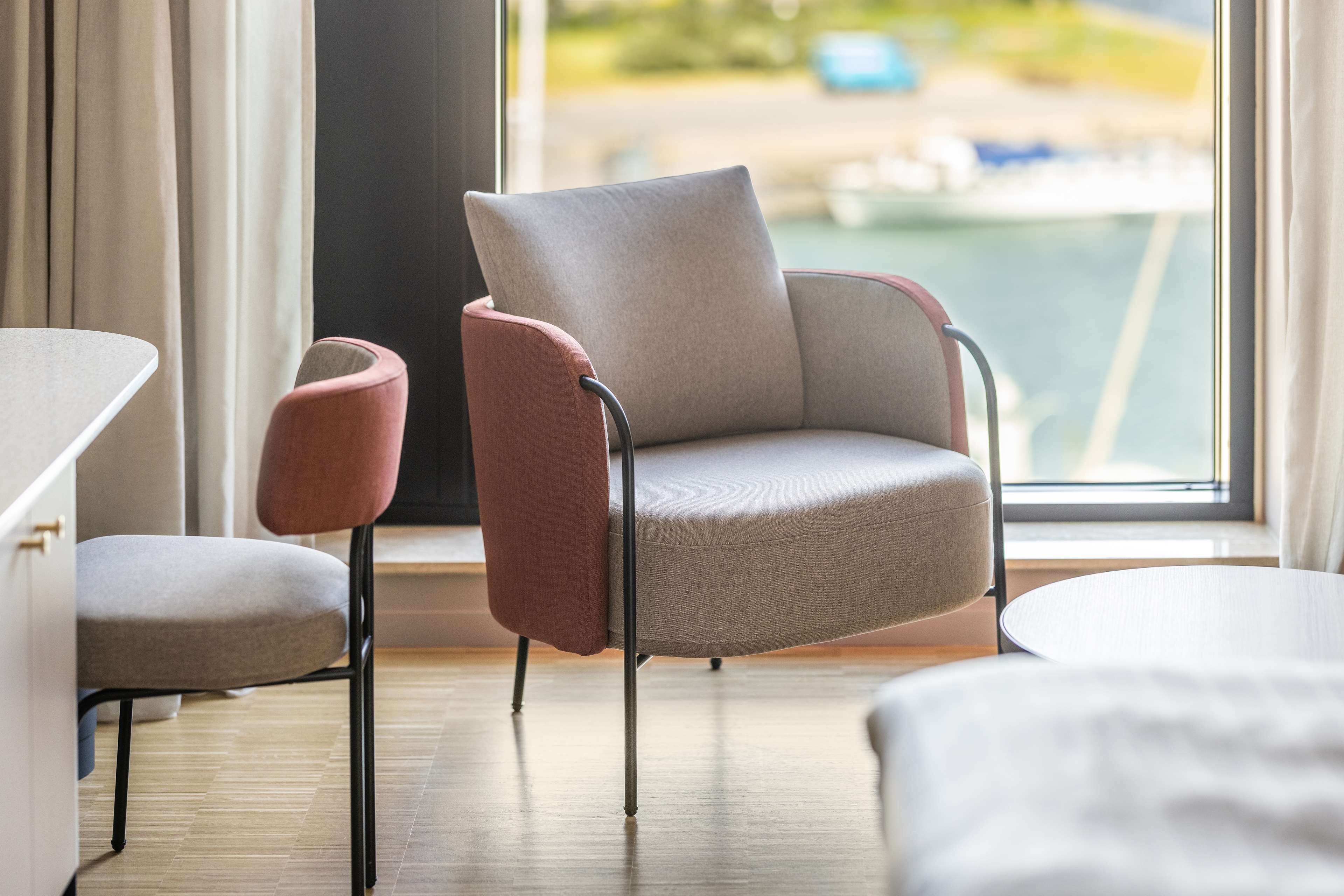 A modern hotel room with a large window, a round table, and two chairs.