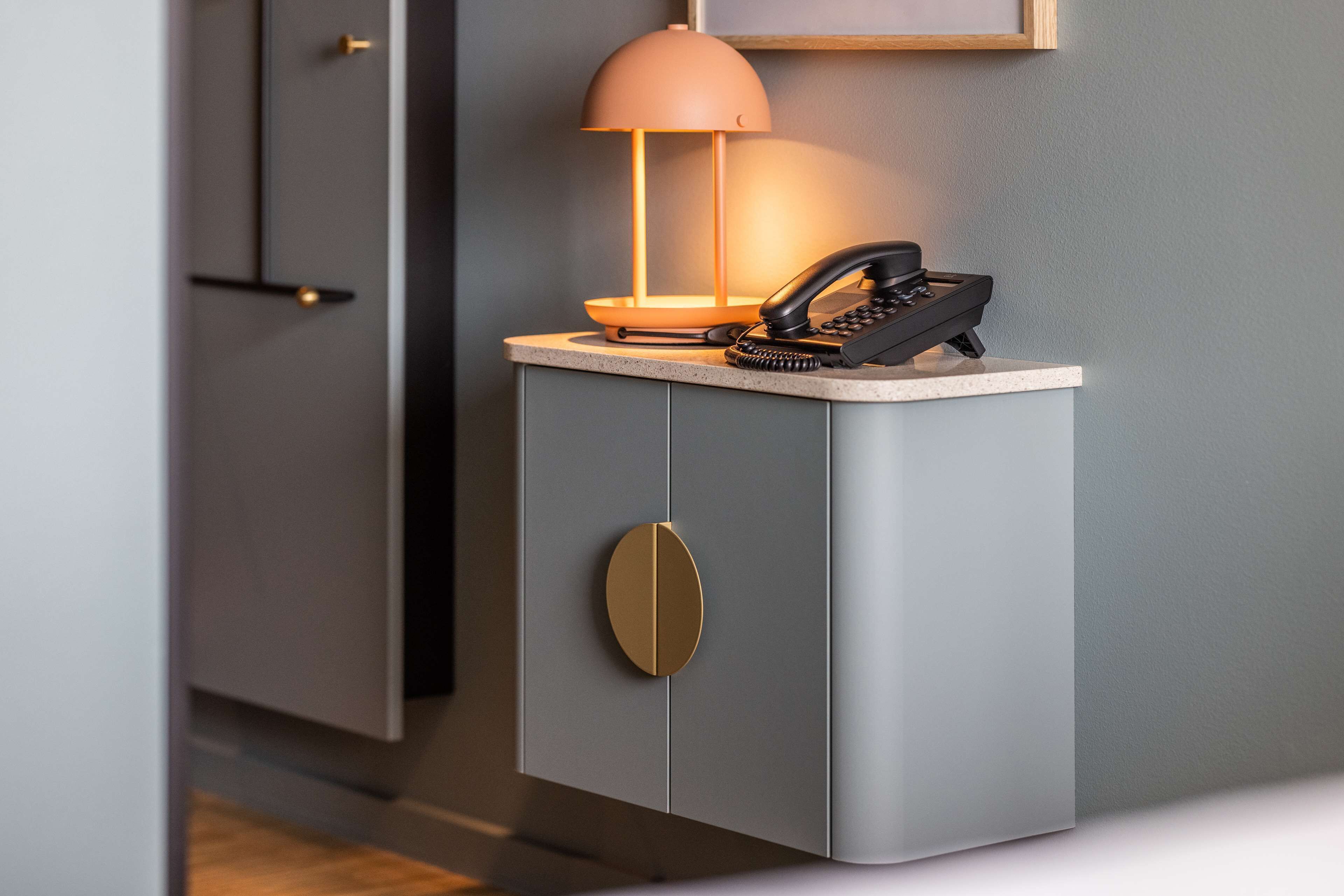 A modern kitchen with a built-in stove, a phone, and a pendant light.