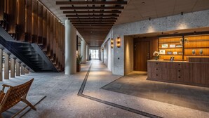 A modern lobby with a central staircase, a reception desk, and a seating area. - Scandic CPH Strandpark (Kastrup)