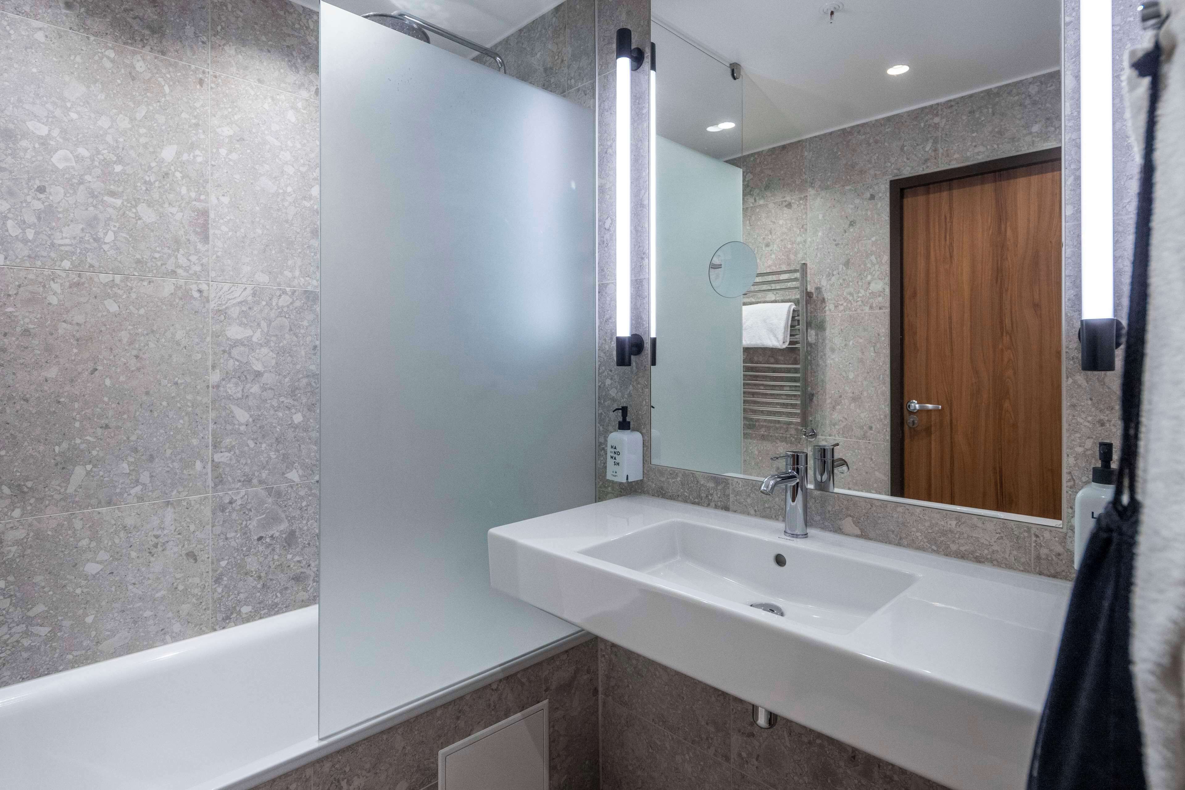 A modern bathroom with a large sink, a mirror, and a shower.