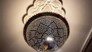 Un lampadario decorativo con motivi elaborati e una sfera riflettente centrale.