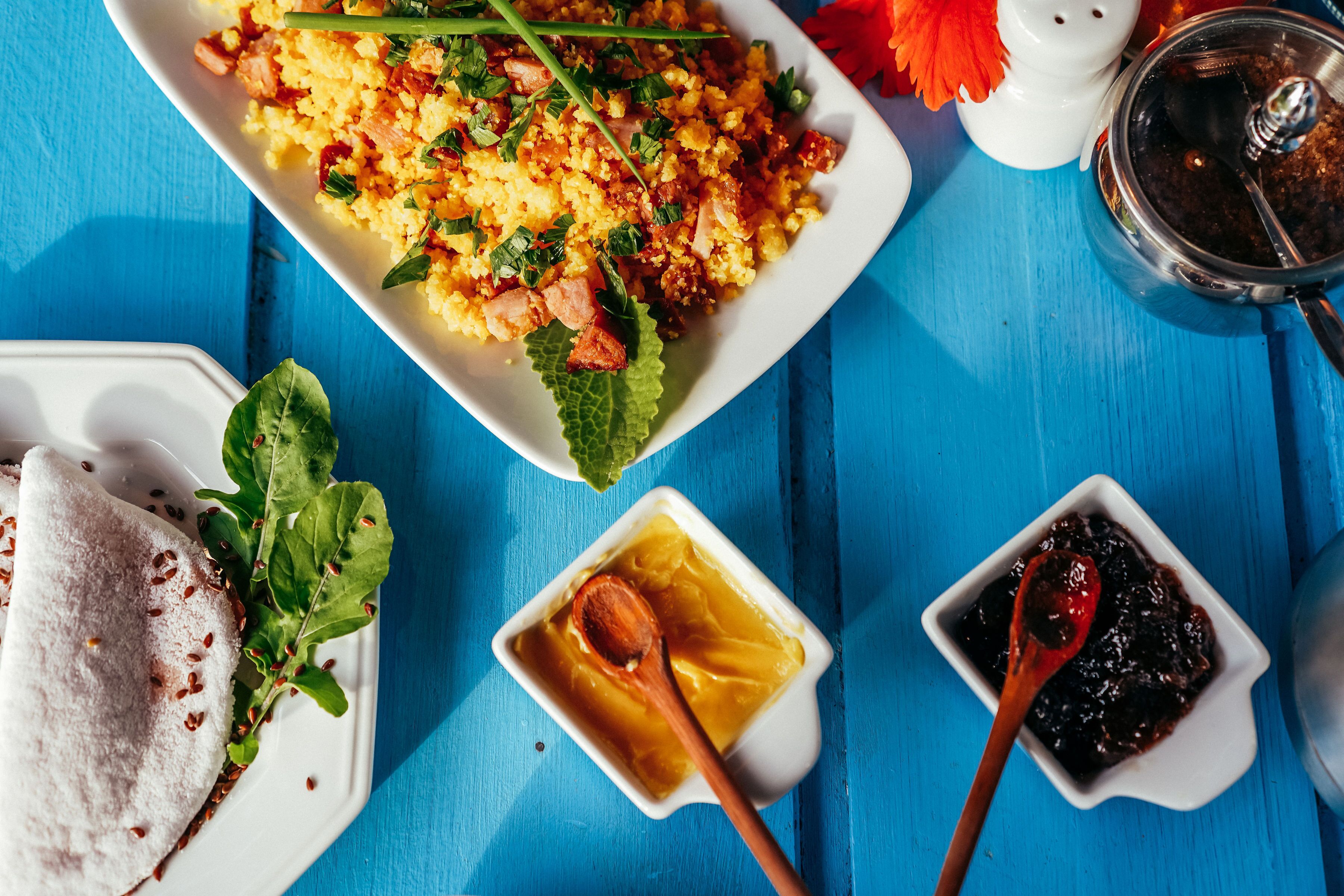 Prato de comida com um acompanhamento de molho e uma xícara de café sobre uma mesa azul.