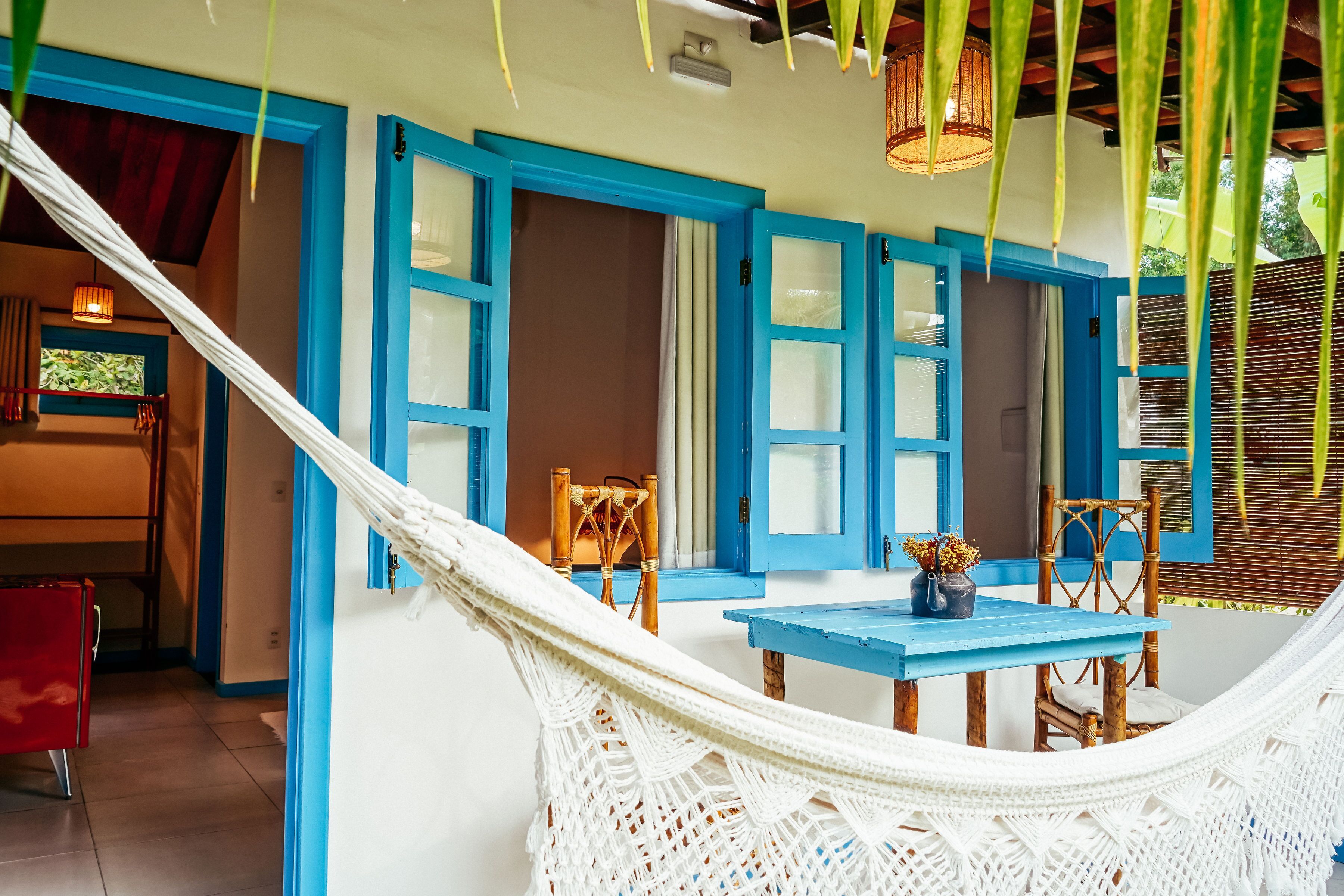 Una hamaca con una mesa y sillas en una habitación con puertas azules y paredes blancas.