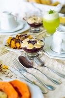 Una mesa de comedor con diversos platos, incluyendo un postre con rodajas de plátano, una bebida verde y una taza blanca.
