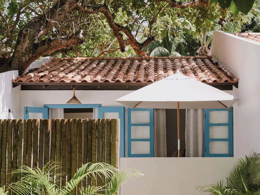 Una casa con techo de tejas, cerca de madera y jardín con diversas plantas.