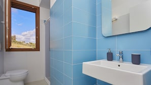 A bathroom with a toilet, sink, and window.