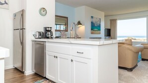 Een moderne keuken met een vast kookeiland, roestvrijstalen apparatuur en uitzicht op het strand.