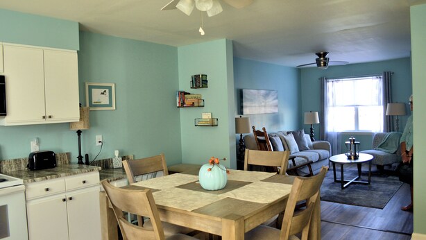 A spacious living area with a dining table, chairs, a sofa, and a TV.
