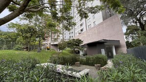 A modern building with a flat roof, surrounded by lush greenery and a playground.