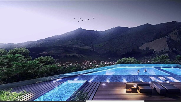An infinity pool with a view of mountains and a cityscape.