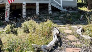 Una casa de dos pisos con un porche cubierto, una bandera y una escalera de piedra.