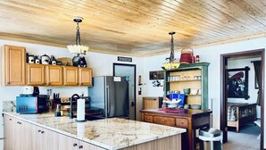 Una cocina con armarios de madera, encimera de granito, refrigerador de acero inoxidable y comedor con mesa y sillas.