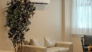 A modern living room with a beige sofa, a black coffee table, and a large potted plant. - D8 Hotel Express (Fortaleza)