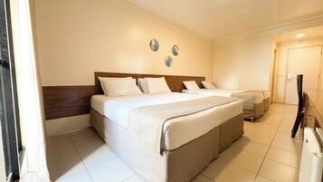 A hotel room with a large bed, a smaller bed, and a desk.