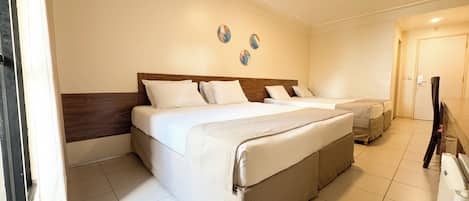 A hotel room with a large bed, a smaller bed, and a desk.