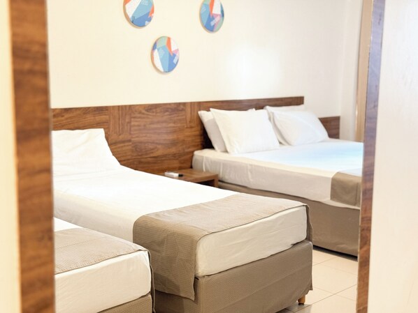 Une chambre d’hôtel avec deux lits simples, une tête de lit en bois et une petite table de chevet.