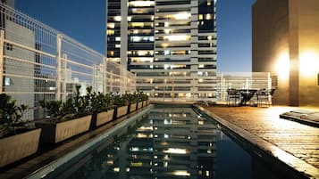 Una piscina al aire libre, sombrillas, sillones reclinables de piscina