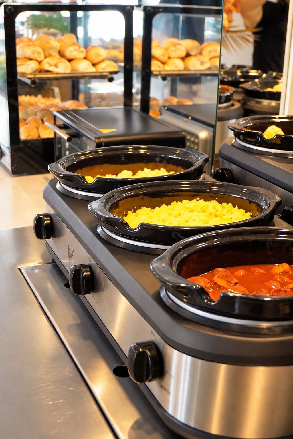 A buffet setup with various food items in black serving dishes on a stainless steel stove.