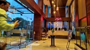 A modern hotel lobby with a reception desk, a neon sign, and a glass storefront. - OYO Rooms Noida Sector 62 (Noida)