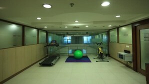 A fitness room with a treadmill, exercise ball, and weights. - OYO Rooms Noida Sector 62 (Noida)