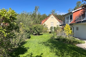 Ein Wohnhaus mit gepflegtem Rasen, einem roten Dach und einem Balkon.