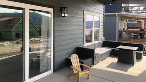 Un área de patio techada con techo de madera, puertas correderas de vidrio y mobiliario exterior.