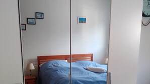 Une chambre à coucher avec un lit, une table de chevet, une lampe et une armoire.