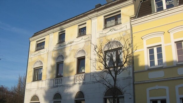 Un immeuble à plusieurs étages de style architectural classique, caractérisé par des fenêtres en arc et des moulures décoratives.