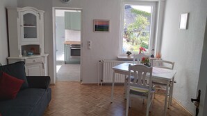 Un espace de vie compact comprenant un coin repas, une kitchenette et une vue par la fenêtre.