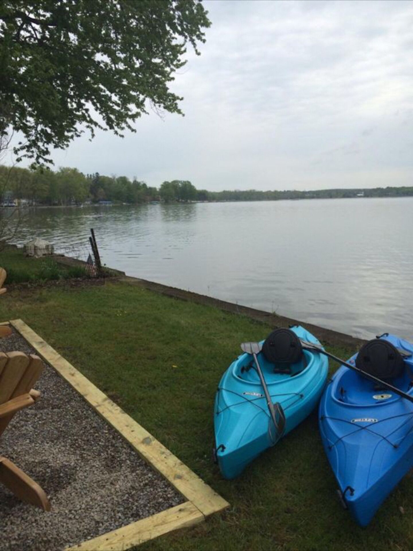 Un cadre idyllique au bord du lac, avec des kayaks et une chaise placée au bord de l’eau.