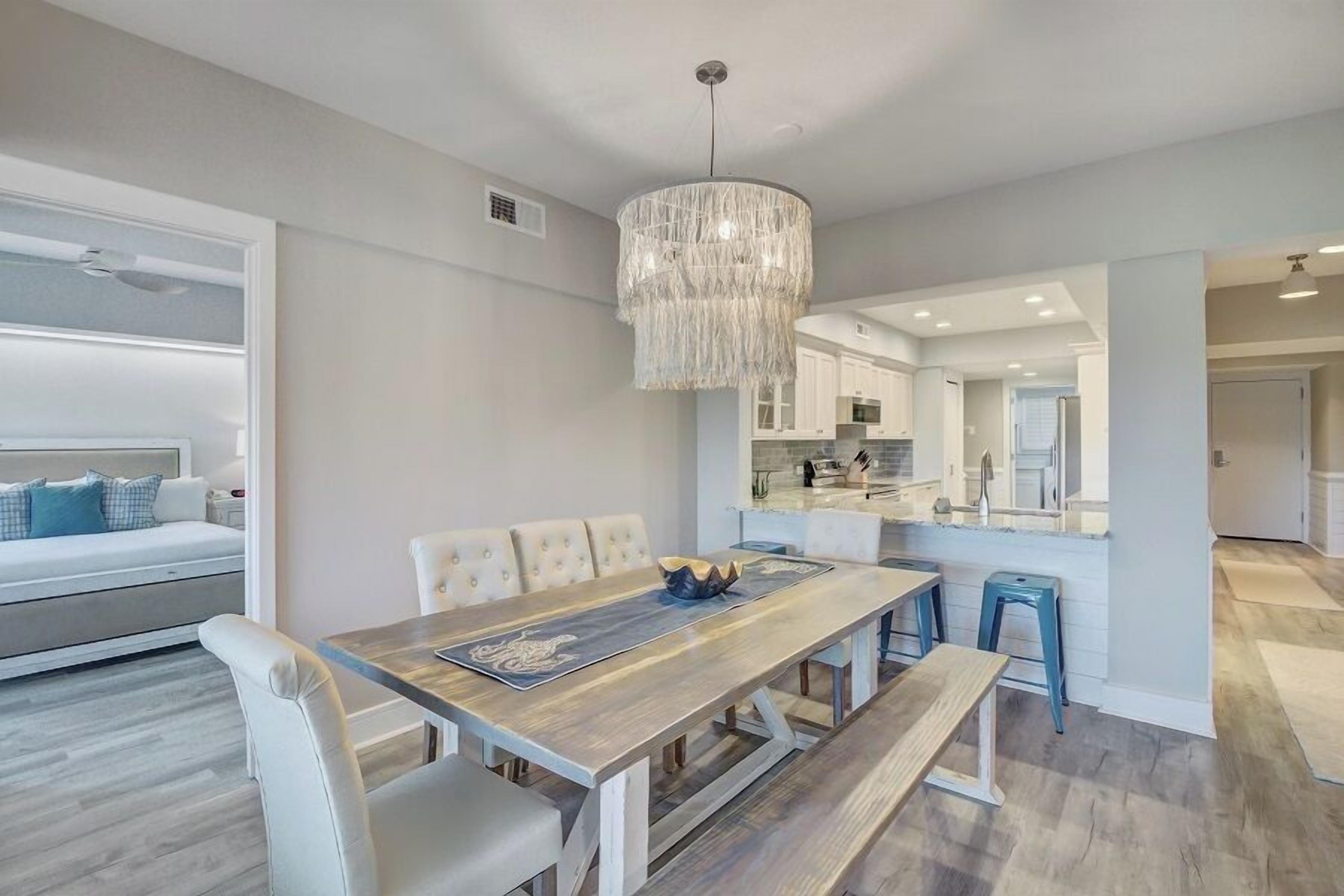A modern kitchen with white cabinets, a central island, and a hanging light fixture.